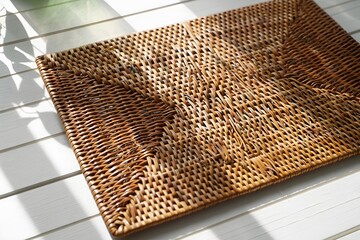 Woven wicker mat on white wooden floor