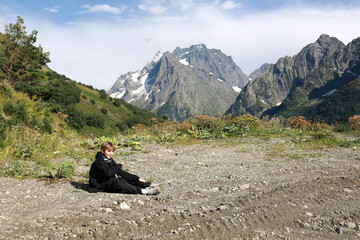 Boy sitting on gravel road in mountains