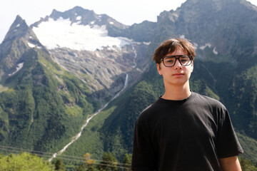 Young man posing near snow-capped mountains in Dombay
