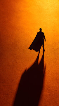 Lone shadowed figure with flowing cape casting long silhouette on warm textured ground, dramatic heroic mood and strong directional light