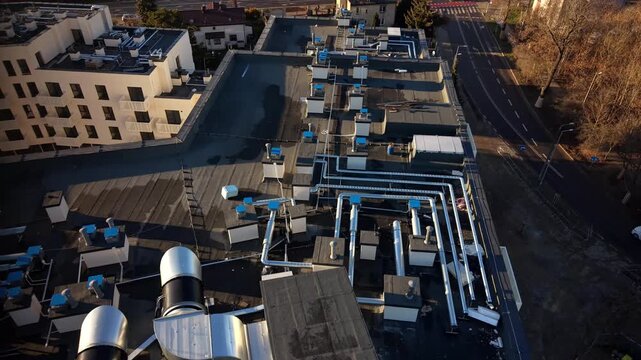 Aerial view of rooftop HVAC ventilation system and industrial ductwork on a modern commercial building &mdash; mechanical plant, ventilation units, ducts and chimneys at golden hour, urban infrastructure