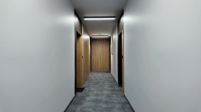 Modern apartment corridor with wooden doors, LED ceiling lights and grey carpet &mdash; minimalist residential hallway, clean symmetrical perspective, no people