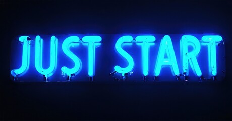 Bright blue neon sign displays words Just Start. Dark background emphasizes glowing text. Simple, motivational message presented visually.
