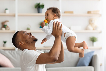 Father Baby Relationship. Happy Black Man Lifting Up His Adorable Infant Son While Playing Together...