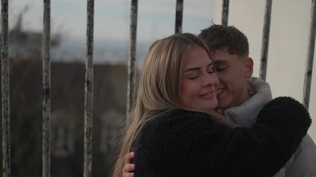 A young couple embraces and shares a kiss in Paris France The romantic scene unfolds with the cityscape visible through iron bars The clip captures a tender moment of love and affection between the tw