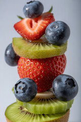 Stack of strawberries, blueberries, and kiwi slices on a white background with copy space