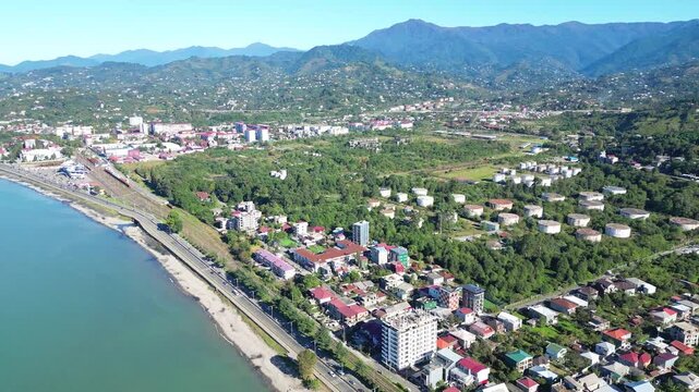 Aerial suburb view near Batumi from sea. 4K horizontal drone footage in clear weather shows residential districts, private houses and a busy road with cars along the Georgian coastline.