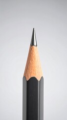 Close-up shot of a sharpened black pencil, showcasing the graphite tip and wooden body.