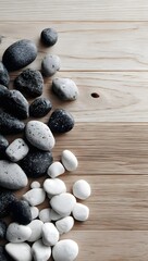 Overhead View of Smooth Dark Gray and Light Gray Pebbles Artistically Arranged on a Pale Wood Background for Tranquil Decor and Balance