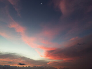 Colorful dusk sky featuring soft pastel clouds and a crescent moon. Tranquil evening scene with smooth gradients, perfect for background, meditation, travel, or inspirational concepts.