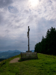 Summit cross wayside shrine against a dramatic sky, on the Grindelalmschneid in the Schlierseer Mountains.