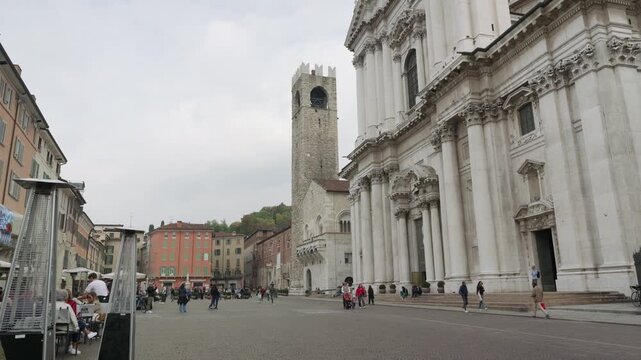 A Close View Of The White Marble Facade Of Duomo Nuovo And The Medieval Pallata Tower, A Historic Brick Structure, Standing In A Brescia Square, Italy.