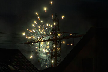 Golden fireworks spreading across night sky behind power pylon, New Years Eve Silvester 2025