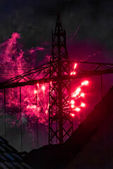 Red fireworks and smoke behind electricity pylon during New Years Eve night, Silvester 2025