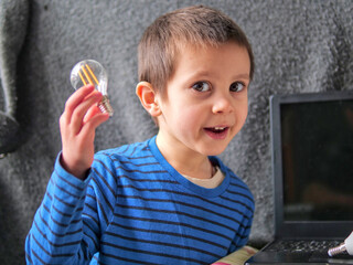 Happy Boy Holding Lightbulb with Enthusiastic Expression during STEM Activity - fun with science