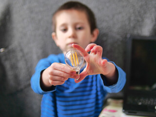 Boy Carefully Inspecting the Filaments of a Clear Lightbulb for Science Study - child Curiously Holding a Vintage-Style Filament Light Bulb