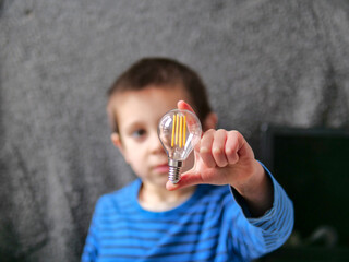 Boy Holding Clear Filament Lightbulb as a Concept for a Bright Idea for science curriculum materials, tutoring services, or STEM workshop promotions
