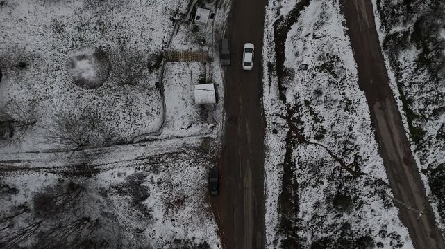 A winter road scene featuring fresh car tracks leading through snow-covered surroundings. The composition conveys movement, journey, and solitude, with a cold seasonal atmosphere and quiet winter land