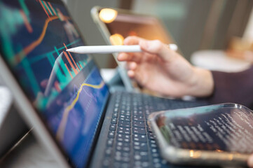 Analyzing financial data on a tablet with a stylus and a smartphone