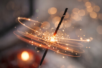 glowing sparkler creating swirling light trails with golden bokeh in a warm festive atmosphere symbolizing celebration magic and joyful moments