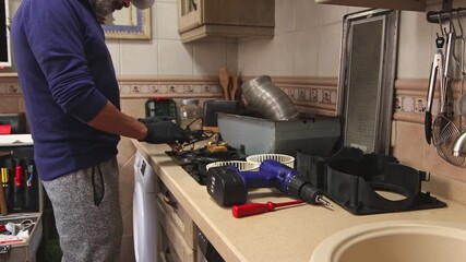 Close-up of a technician examining the circuit board inside a kitchen extractor hood. Appliance repair, electronics maintenance, home service, ventilation system, professional work.