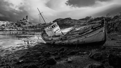 The Scottish ruins of Castle Moil in the background of a shipwreck in Kyleakin, UK