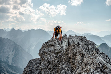 Mountaineer standing on a rocky ridge with breathtaking panoramic view over countless peaks in Tyrol, Austria, dramatic alpine landscape and clear sky.