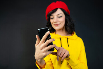a woman looking at a smartphone against a black background.