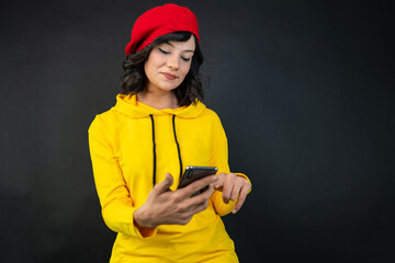 a woman looking at a smartphone against a black background.