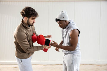 One man helps another adjust his boxing gloves, symbolizing friendship and teamwork in the world of sports and training.