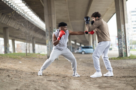 Two athletes engage in sparring, emphasizing skill and technique while showcasing their athleticism in an urban setting.