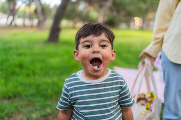 Young boy with wide open mouth showing a candy, celebrating easter outdoors © pablo