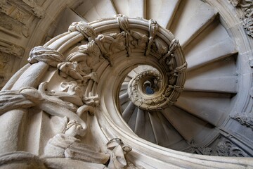 Intricate spiral staircase with ornate stone carvings in historic building