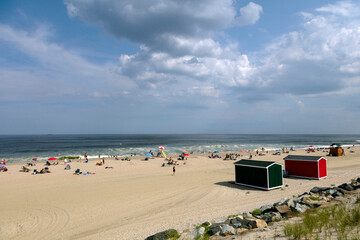 Obraz premium Bright sunlit beach scene with colorful cabins and people