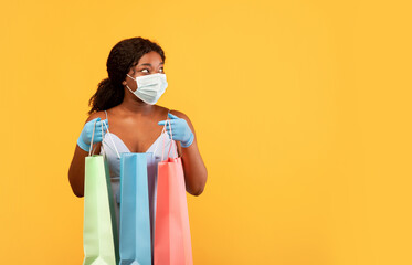 Safe shopping during covid. African American woman wearing face mask and rubber gloves, holding...