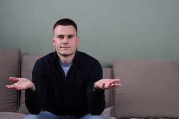 confused and unsure young man sitting on sofa