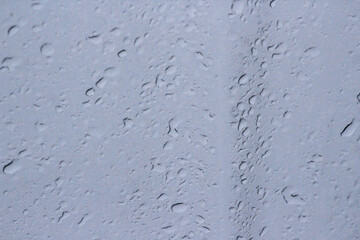 Transparent plastic texture with water drops. Transparent white plastic background. Wet transparent polyethylene film with droplets of water after rain. Water drops close-up.
