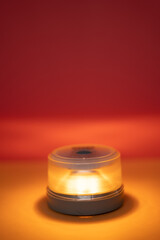 v16 beacon Portable illuminating signal light glowing amber against a warm red and orange background
