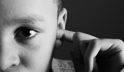 deaf boy and suffering from deafness and hearing loss on black grey background with people stock photo stock image	