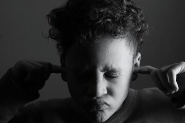 deaf boy and suffering from deafness and hearing loss on black grey background with people stock...