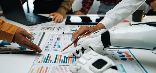Teamwork in action as a robot hand assists in analyzing data reports. Modern office setting...