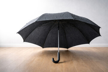 A black umbrella with water droplets in the room.