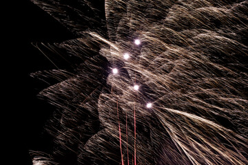 Spectacular silver fireworks explode above city with sparkling trails and bursts