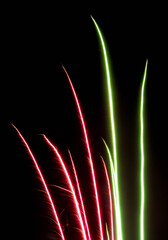 Red and Green Firework Light Trails Rising on Black Background