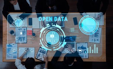 A modern business meeting features professionals collaborating around a table with technology showcasing open data insights and analytical visuals in an office setting. Trope