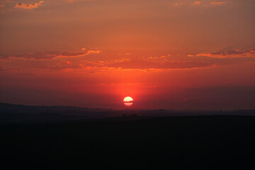 Vibrant sunset over field with clouds orange