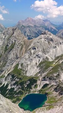Vertical aerial drone view of the Alps mountains, with Coburger Hut located near the scenic lakes Seebensee and Drachensee on a bright, sunny summer day.	