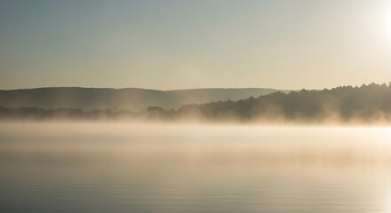 A serene lake landscape with mist rising from the water at sunrise