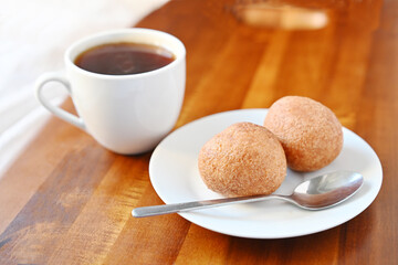A white cup of black coffee and two round pastries on a wooden tray. Cozy breakfast or snack break...