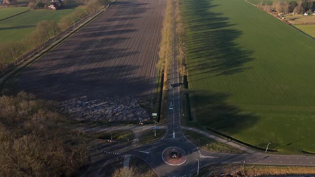 Tranquil Treebordered Street Featuring Circular Junction And Expansive Shadows Crossing Rural Land